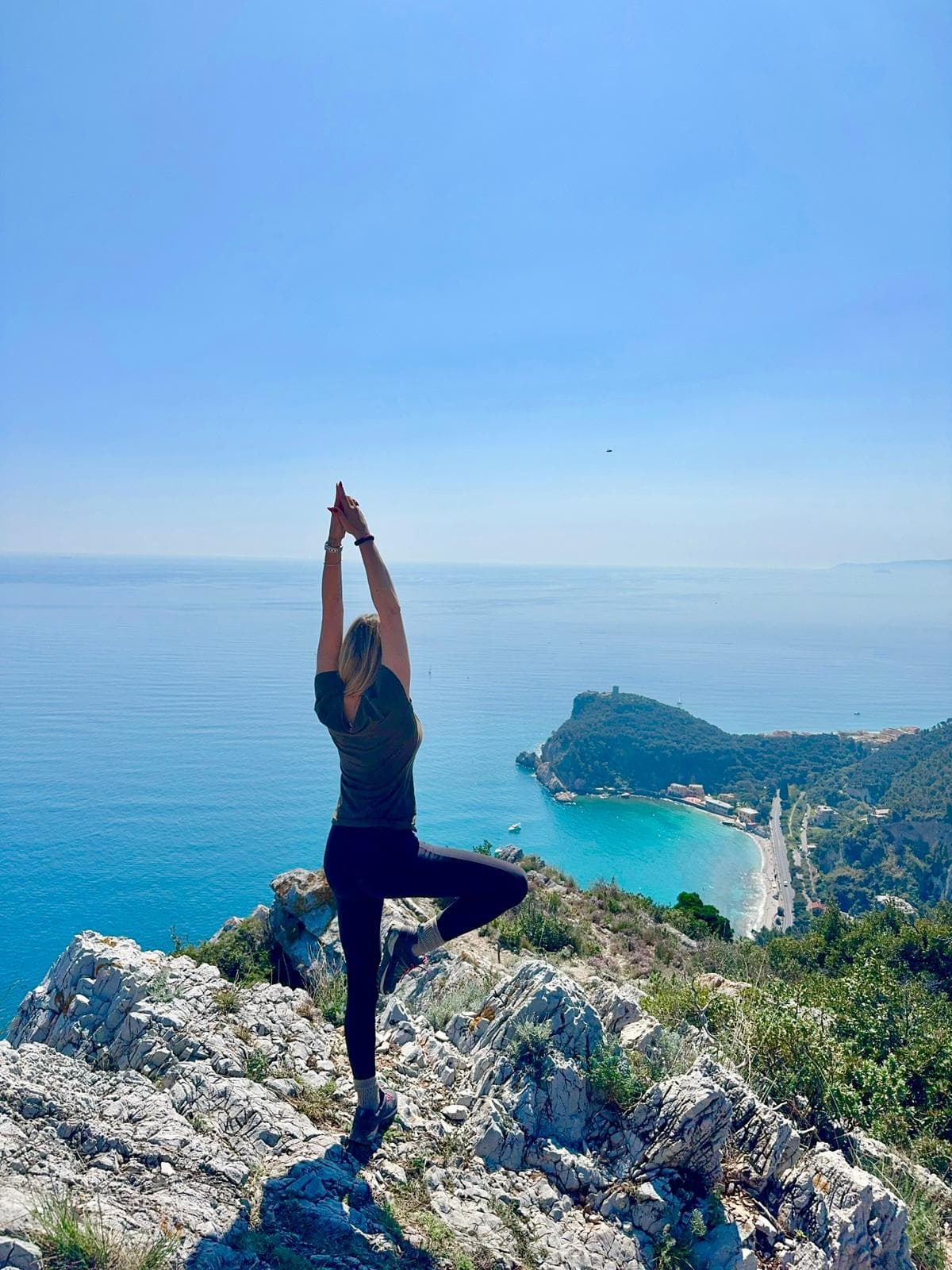 Silvia in tree pose sulla scogliera con vista sulla baia